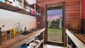 Uma cozinha com prateleiras de madeira, uma pia e vista para o exterior.