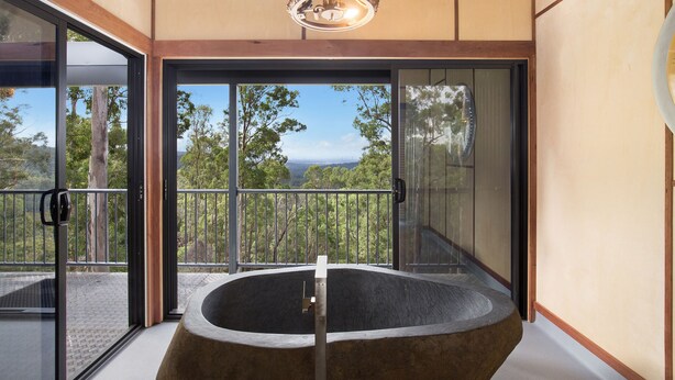 Um interior moderno com uma ampla porta de vidro que dá para uma varanda, uma área de estar circular e um lustre.