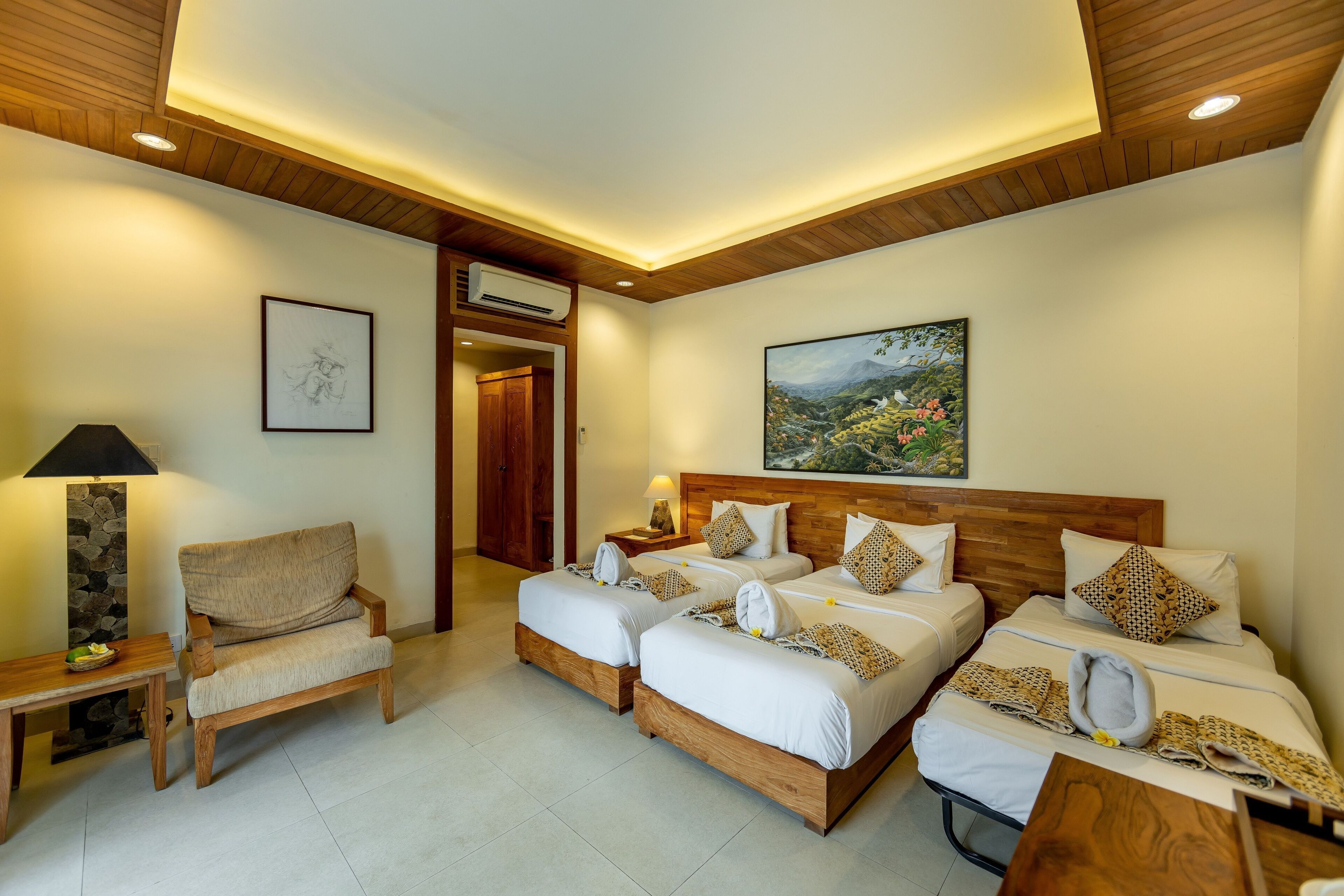 A hotel room with two beds, a wooden ceiling, a painting, and a stone wall.