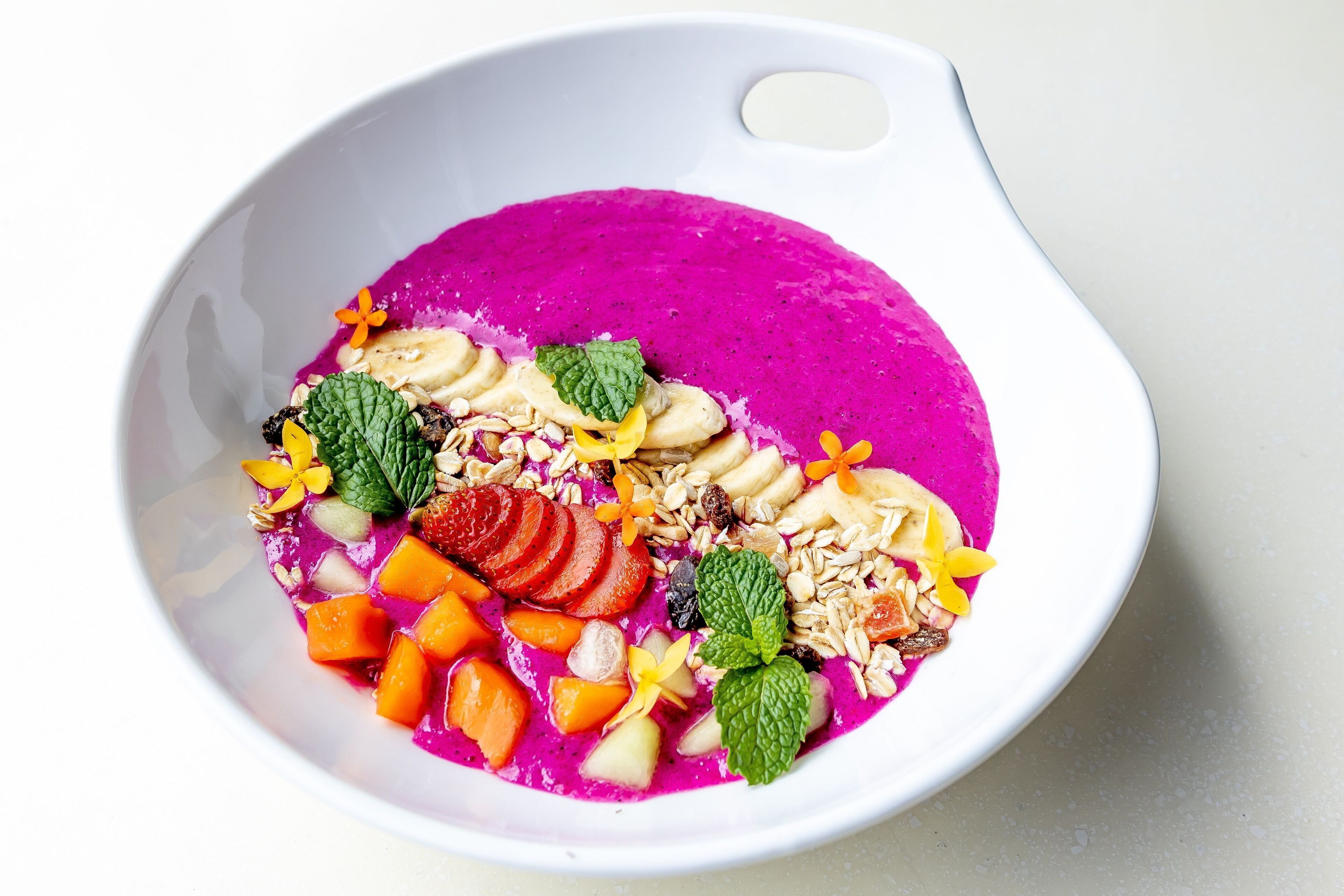 Un tazón de batido colorido con varias frutas y nueces.