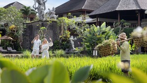 Un bâtiment traditionnel avec un toit en tuiles, entouré d’une végétation luxuriante et d’un jardin bien entretenu.
