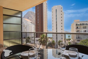 Varanda com mesa posta para refeições, com vista para paisagem urbana com edifícios e montanha.