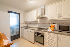 A modern kitchen with white cabinets, a stainless steel range hood, a microwave, and a dishwasher.