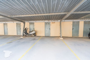 A parking garage with multiple doors, some of which are open, and a scooter parked in one of the open doors.