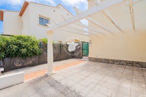 A covered outdoor area with a stone wall, a white pergola, and a paved path leading to a building entrance. - CostaBlancaDreams - Casa Alis in Calpe (Calpe / Calp)