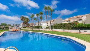 A swimming pool with a clear blue water, surrounded by palm trees and a building with a tiled roof. - CostaBlancaDreams - Casa Alis in Calpe (Calpe / Calp)
