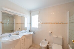 A bathroom with two sinks, a mirror, a bidet, and a toilet.