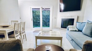A living room with a glass-top coffee table, a sofa, and a television. - Tempe town house near ASU. only 2 miles away. (Tempe)