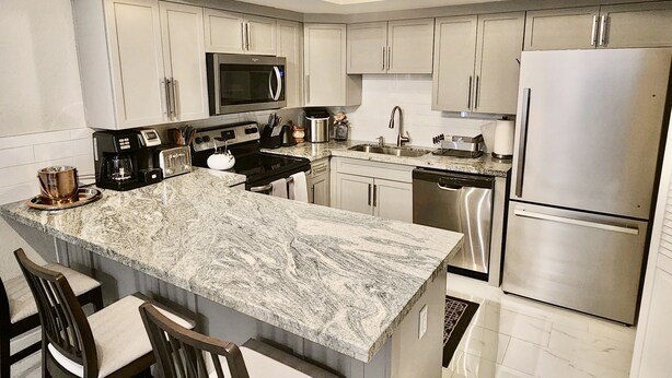 A modern kitchen with a marble island, stainless steel appliances, and a two-basin sink. - Tempe town house near ASU. only 2 miles away. (Tempe)