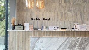 A reception desk at Double J Hotel with a marble counter, two hanging pendant lights, and a view of greenery outside. - Double J Hotel (Chiang Mai)
