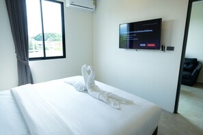 Ein Hotelzimmer mit Bett, Wandfernseher und einem Fenster mit Vorhängen.