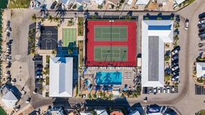 An aerial view of a resort with multiple tennis courts, a swimming pool, and a parking area.