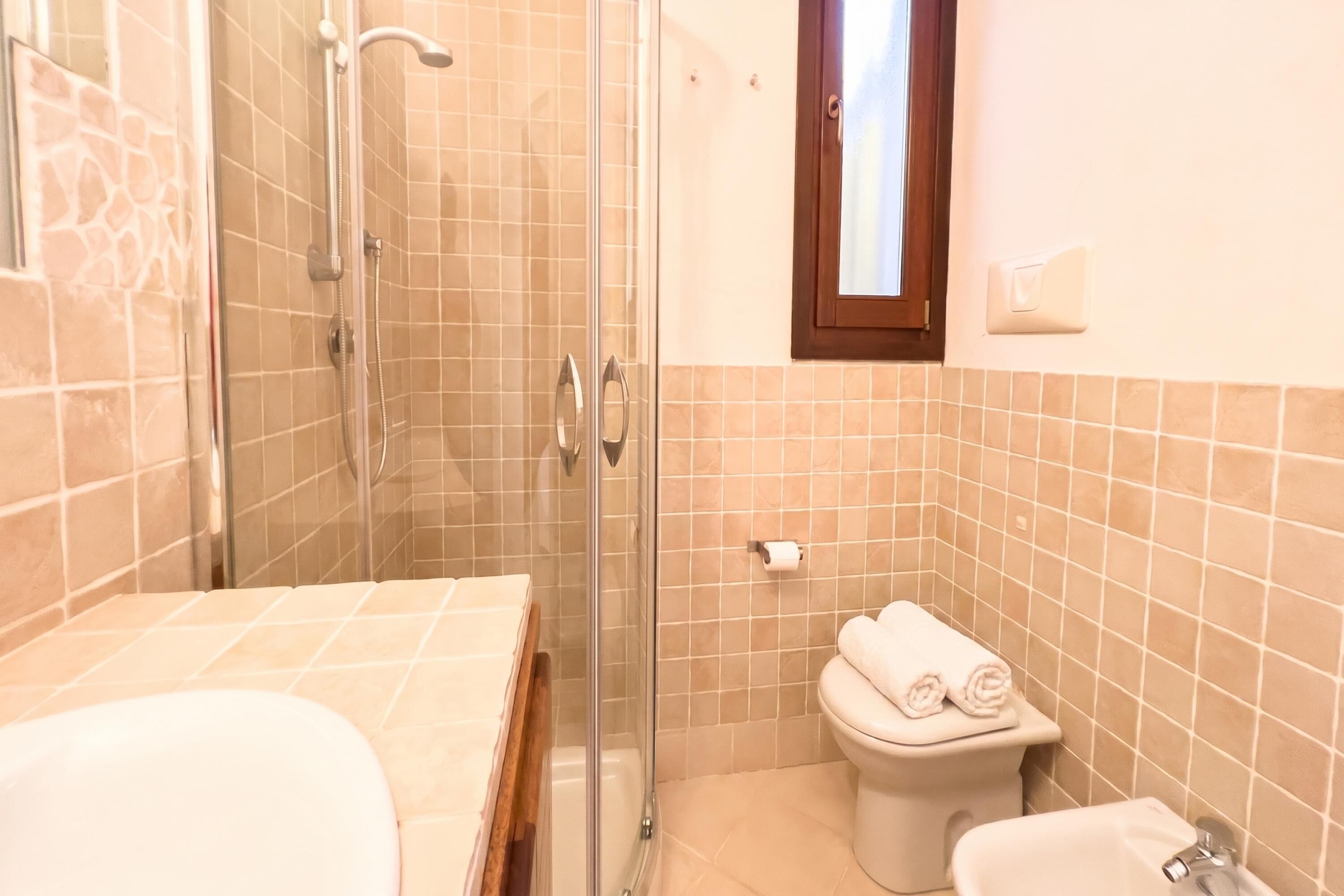 Un baño con ducha de vidrio, inodoro y lavabo.