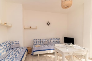 Quarto com cama, escrivaninha, cadeira, televisão e estante.