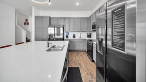 A modern kitchen with grey cabinets, stainless steel appliances, and a large island.