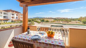 Un balcón con mesa lista para comer, con vista a una piscina y edificios.
