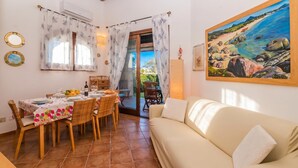 Un coin repas avec une table dressée pour quatre personnes, un canapé et un tableau accroché au mur.