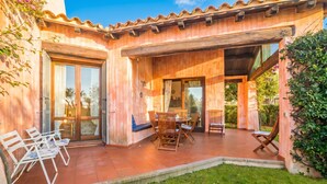 Une villa en bois dotée d’un patio, d’un espace salon extérieur et offrant une vue sur le jardin environnant.