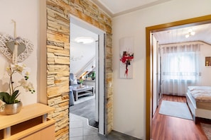 Quarto com cama, janela com cortinas, piso de madeira e parede de pedra.