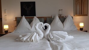Una camera d'albergo con un letto, cuscini, un'opera d'arte appesa al muro, lampade da comodino e un tavolino di fianco al letto.