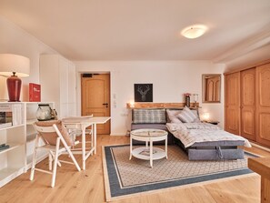 Une pièce confortable et bien éclairée, avec un lit, une petite table, une chaise et une bibliothèque.
