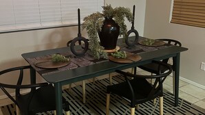 A dining table with a dark tablecloth, two black chairs, a vase with green plants, and a patterned rug. - Swanky Super Bowl House 2 miles from Stadium. (PHOENIX)