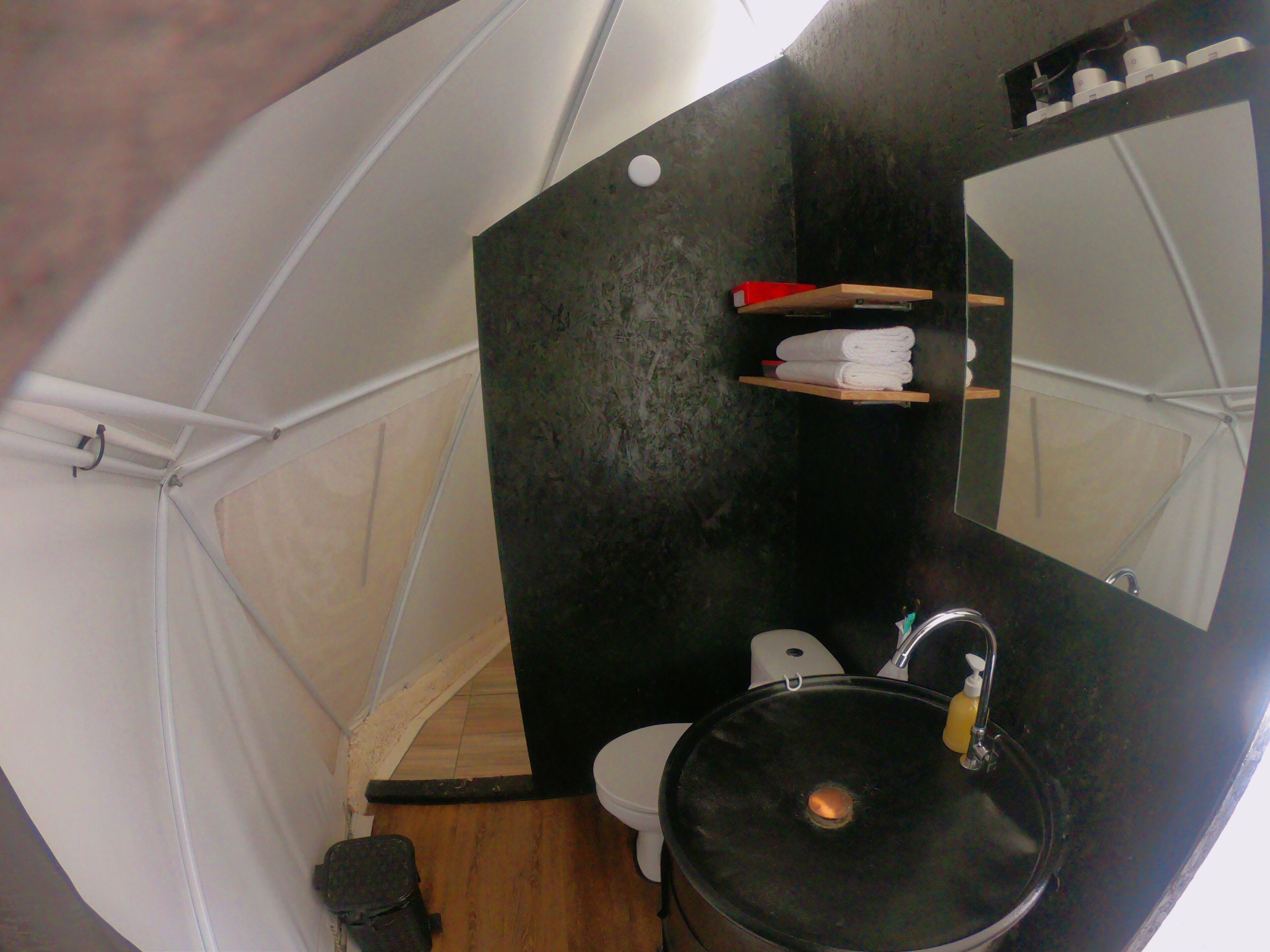 Une petite salle de bain avec un lavabo noir, des toilettes et un miroir.