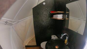 Une petite salle de bain avec un lavabo noir, des toilettes et un miroir.