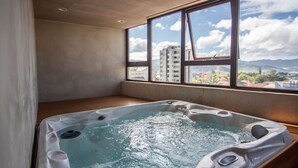 A hot tub in a room with a large window overlooking a cityscape. - Digital Nomads Dream + Sauna (Curridabat)