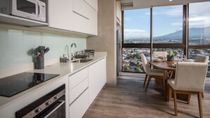A modern kitchen with a microwave, stove, and dining area with a view of a cityscape. - Digital Nomads Dream + Sauna (Curridabat)