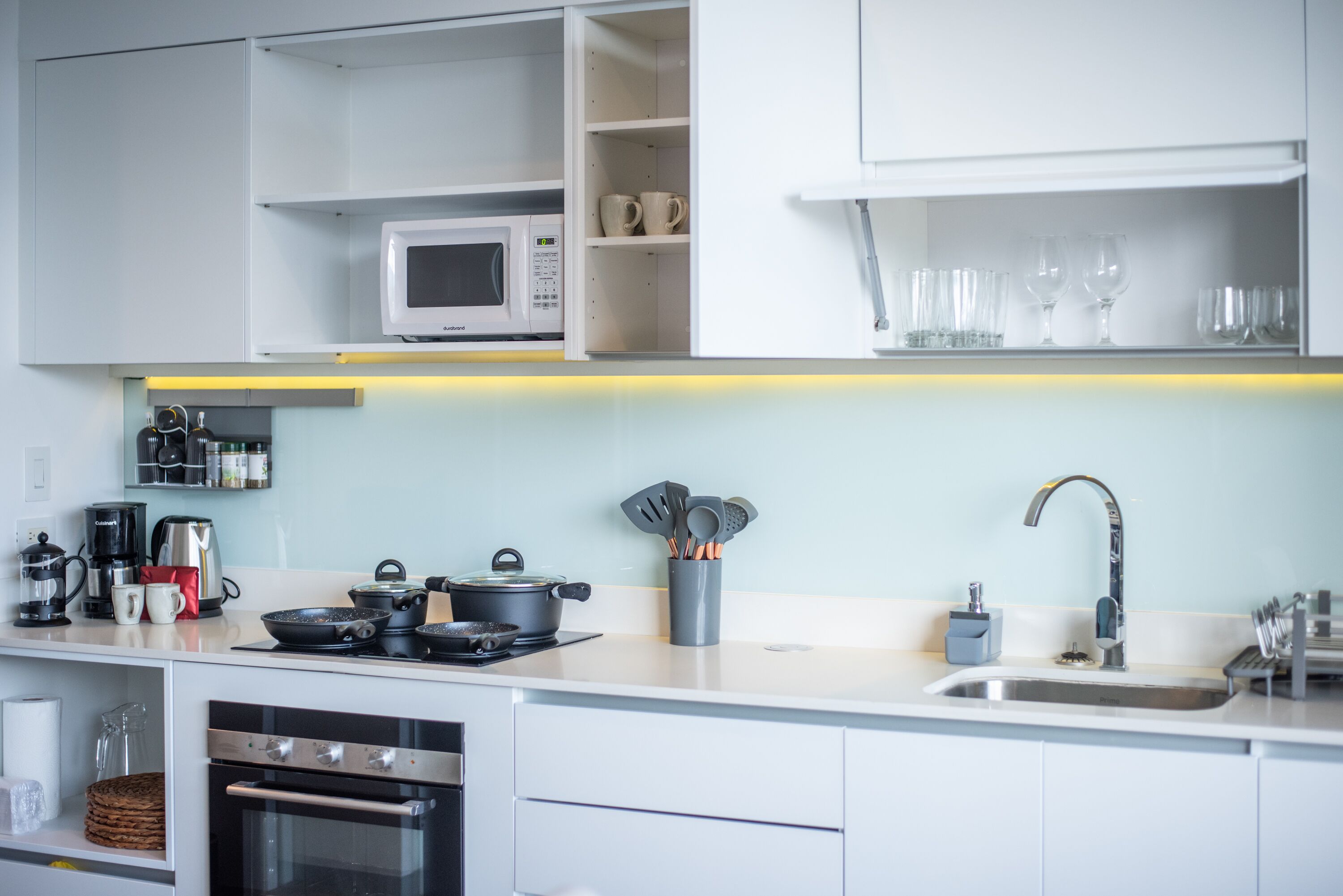 Una cocina moderna con armarios blancos, un microondas, una estufa y un lavamanos.