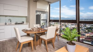 A modern kitchen with a dining area, large windows with a city view, and a potted plant on the table. - Digital Nomads Dream + Sauna (Curridabat)