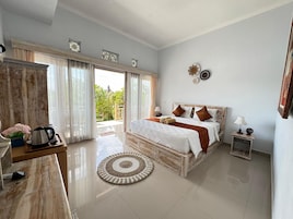 Un dormitorio espacioso con una cama grande, un escritorio de madera, una cafetera y vistas al exterior.