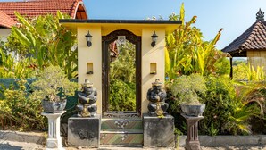 A traditional gate with two statues, surrounded by lush greenery and a tiled roof in the background. - Kaylas Hill Resort (Penida Island)