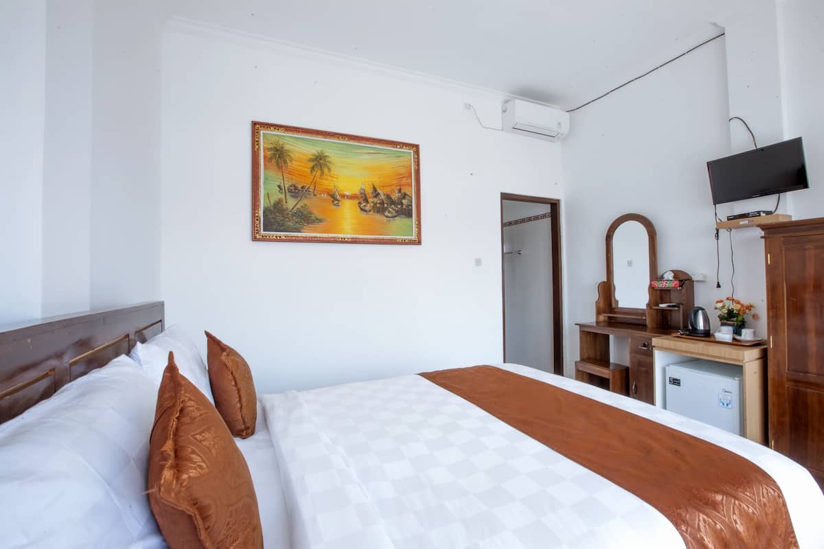 A hotel room with a bed, a desk, a television, and a painting on the wall.