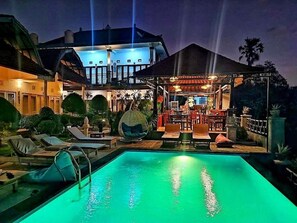 Un espace piscine avec des chaises longues et un coin bar avec des tables et des chaises.