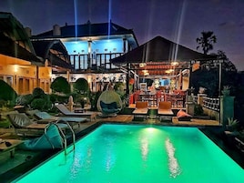 Un área de piscina con sillones de descanso y un bar con mesas y sillas.