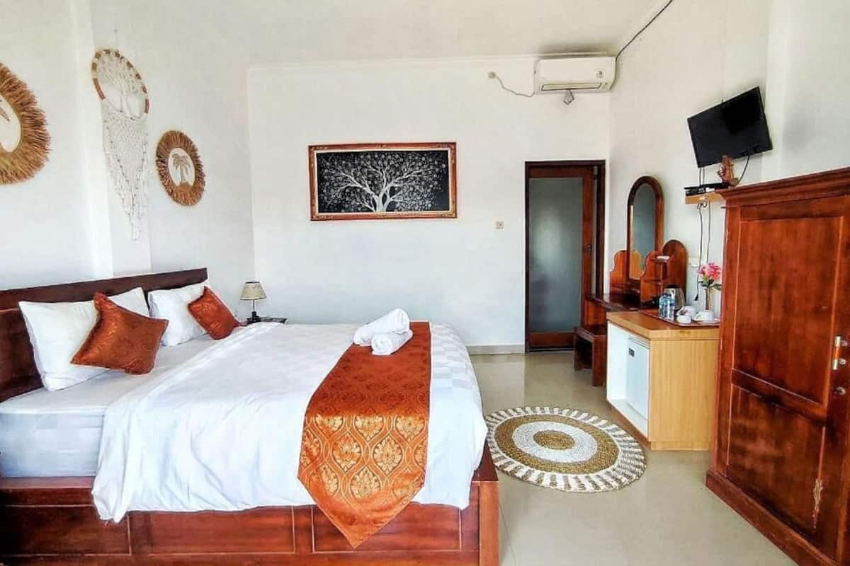 A hotel room with a wooden bed, a desk with a television, and a mirror.