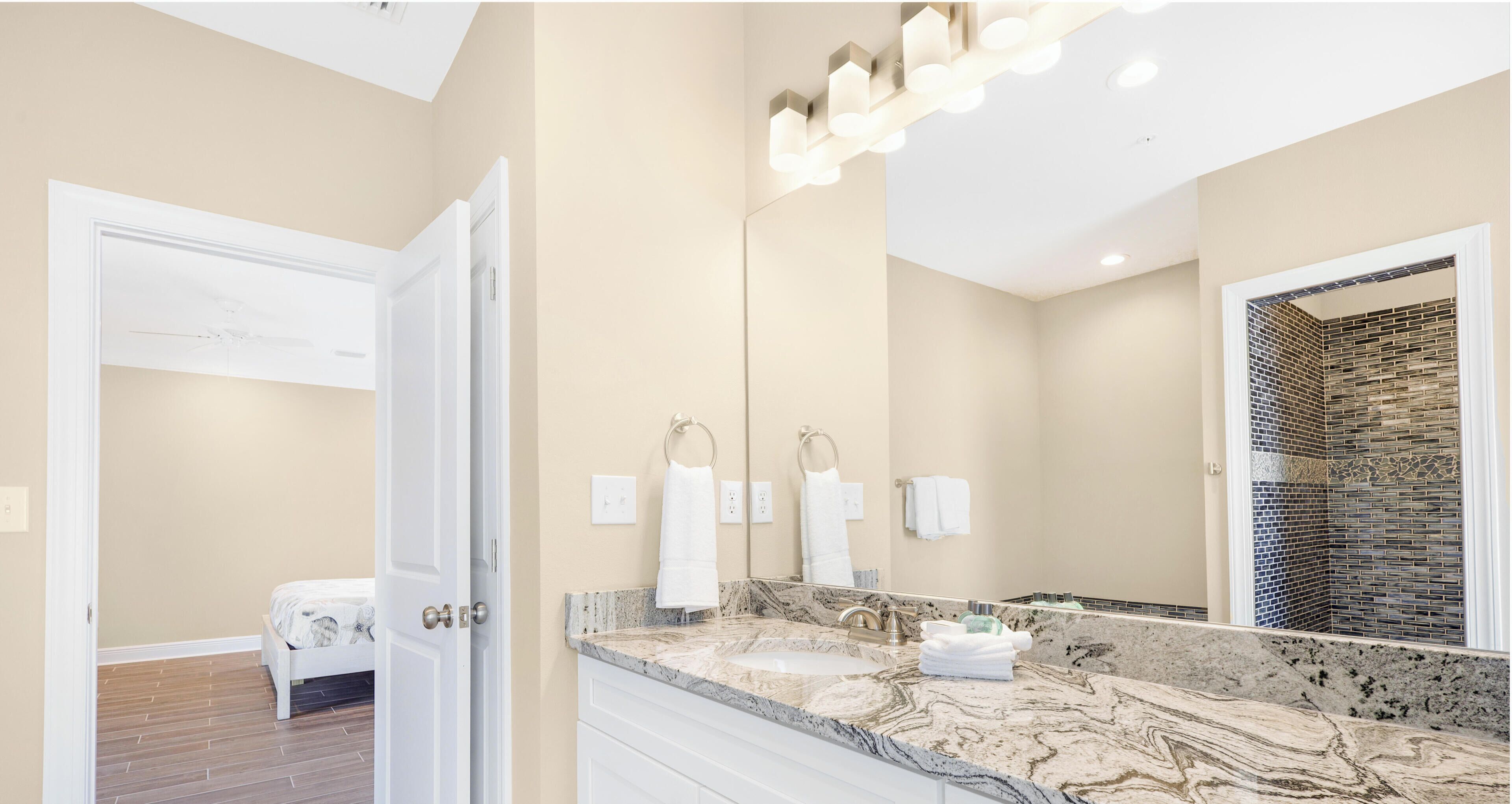 Une salle de bain moderne avec un lavabo en marbre, un grand miroir et un ventilateur de plafond.
