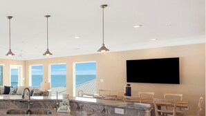 A spacious kitchen with a large island, white cabinetry, and a view of the ocean.