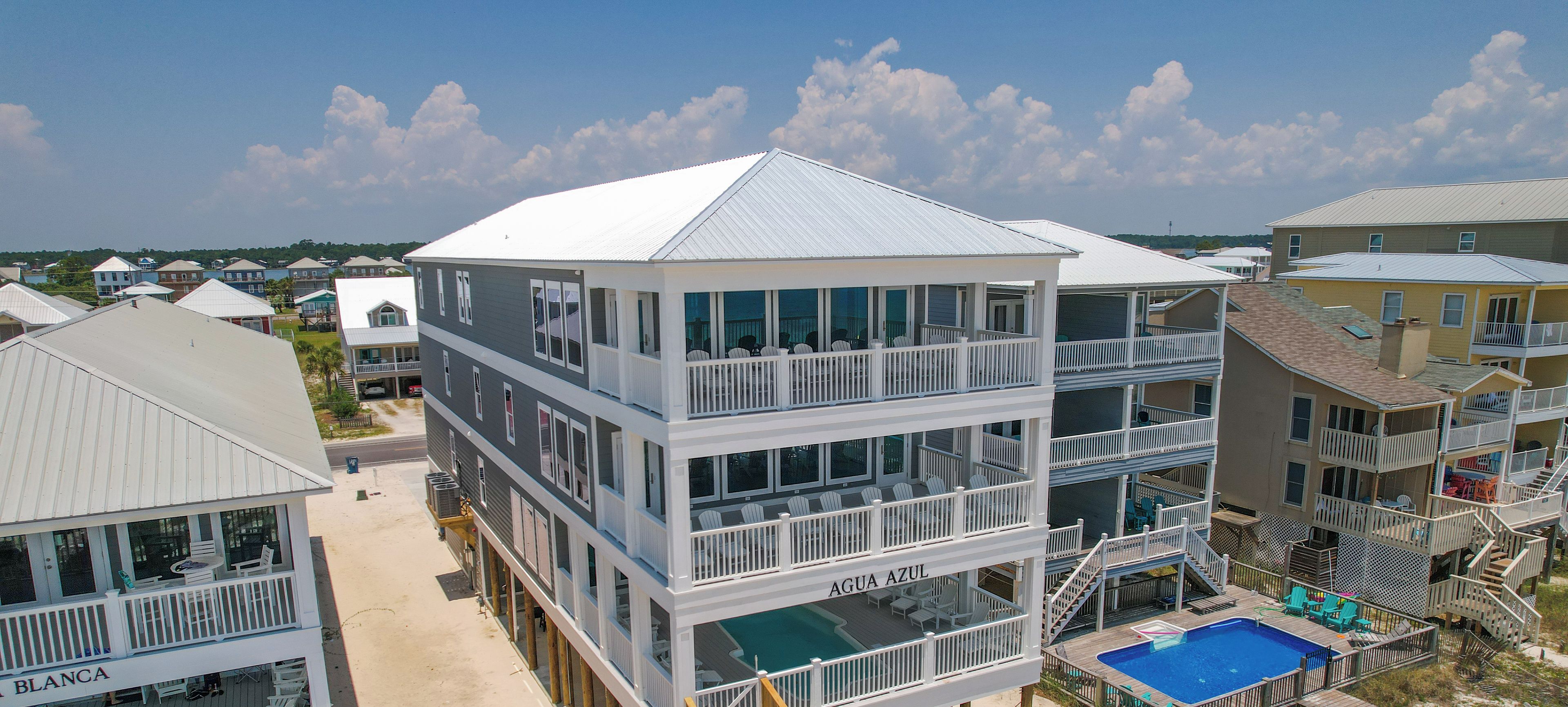 A multi-story building with balconies, a pool, and a sign for 'Kaiser Vacation Rentals'.