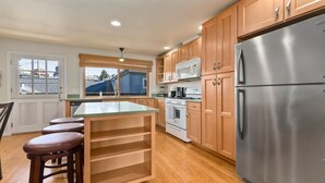 A kitchen with wooden cabinets, a stainless steel refrigerator, a microwave, and a stove. - Capitola Sea Breeze Retreat (Capitola)