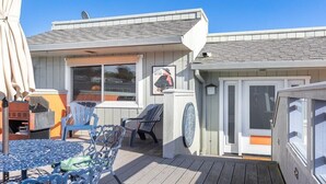 A covered outdoor area with a table and chairs, a grill, and a small building with a window and a door. - Capitola Sea Breeze Retreat (Capitola)