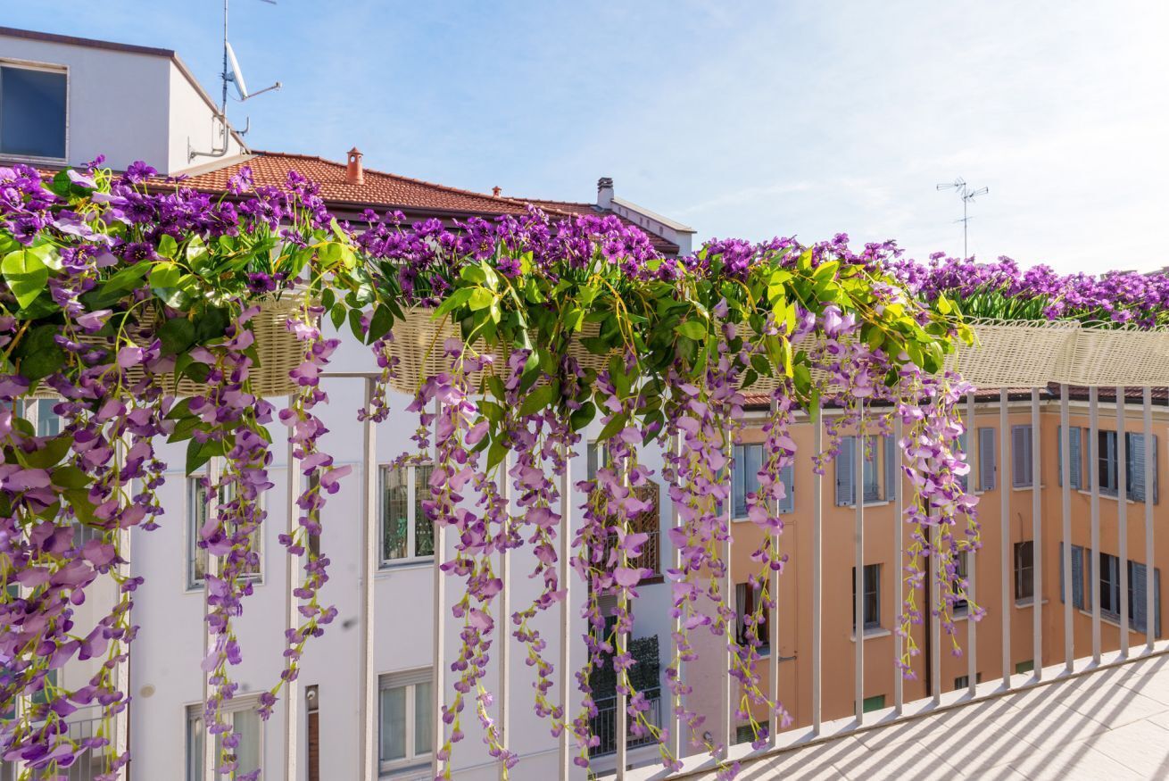 Ein Gebäude mit einem Balkon, der in violette Blüten getaucht ist.