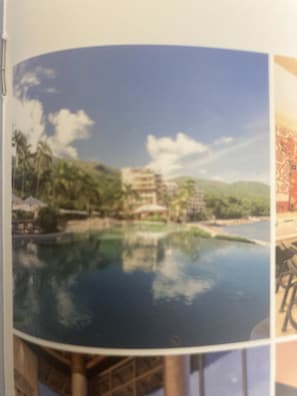 Ein rundes Foto von einem Resort mit Pool, Palmen und einem Gebäude.