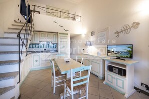 A compact kitchen with a dining area, a staircase, and a television. - 22BAIADELFARO - 22 BAIA DEL FARO (Palau)
