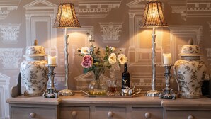 A decorative table with two lamps, two candles, a vase with flowers, and two ornate vases.