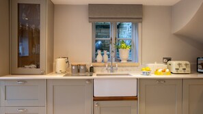A modern kitchen with a built-in dishwasher, a window with a view of a stone wall, and a variety of kitchen appliances. - Pineapple Spa Cottage, Lower Swell - sleeps 4 guests in 2 bedrooms (Lower Swell)