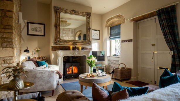 A cozy living room with a fireplace, comfortable seating, and a large mirror.