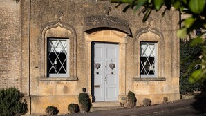 A stone building with two arched windows and a central door, each with diamond-patterned glass.
